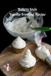 Two cupcakes with vanilla frosting on a round board.