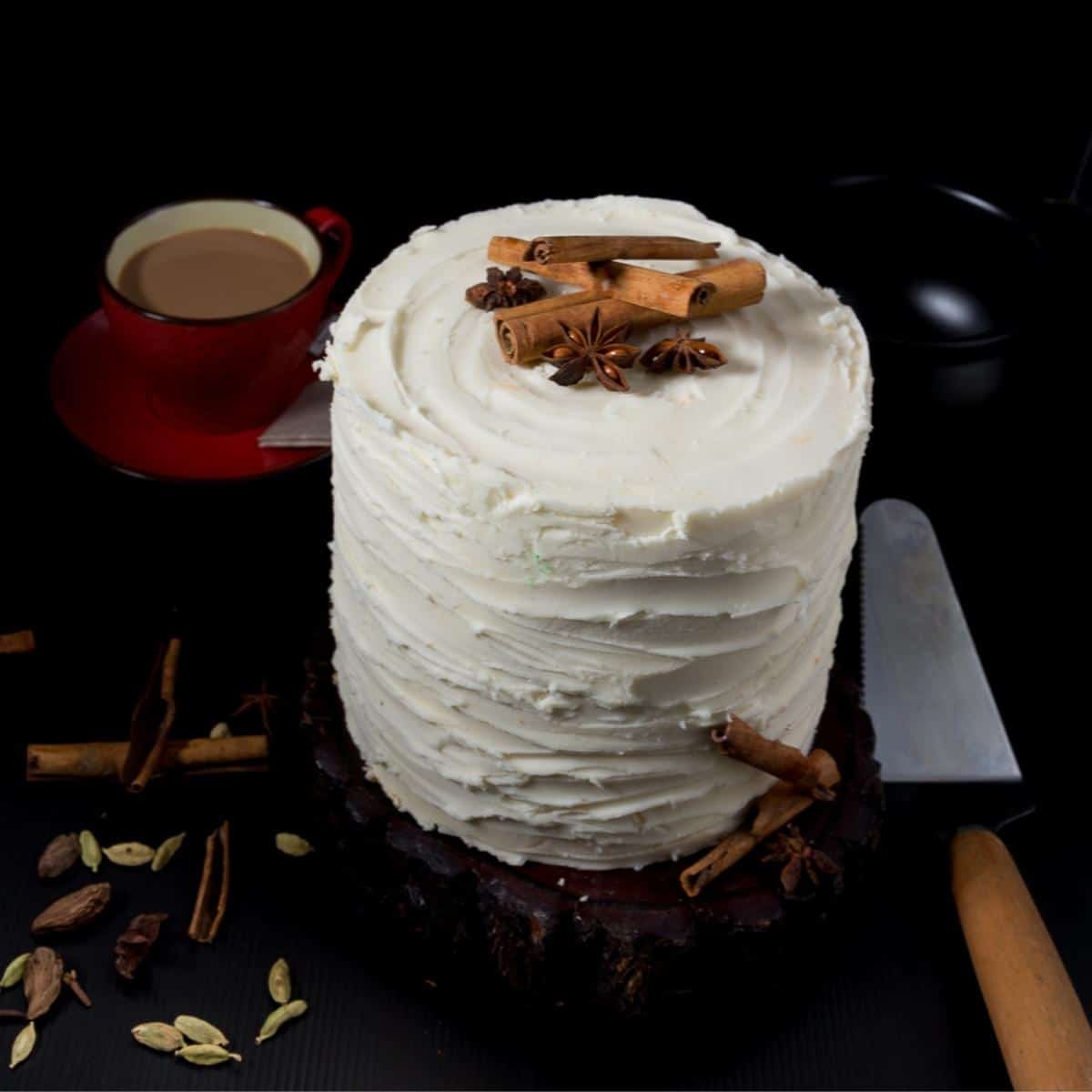 A layer cake with buttercream frosting and whole chai spices on top.