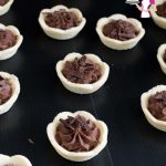 Mini chocolate mousse tarts on a table.