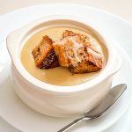 A bow with potato soup and croutons.