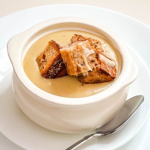 A bow with potato soup and croutons.