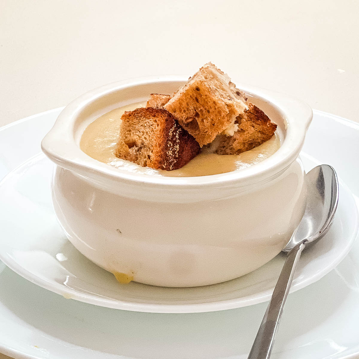 A white bowl with potato soup.