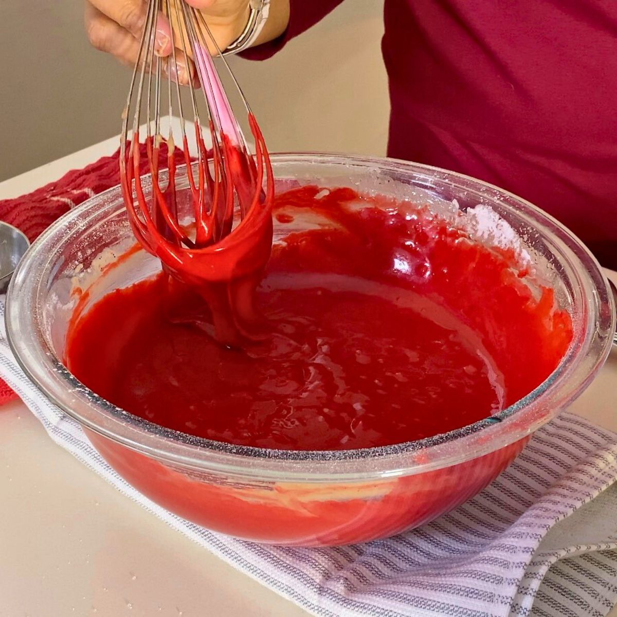 A glass bowl with red velvet cake batter.