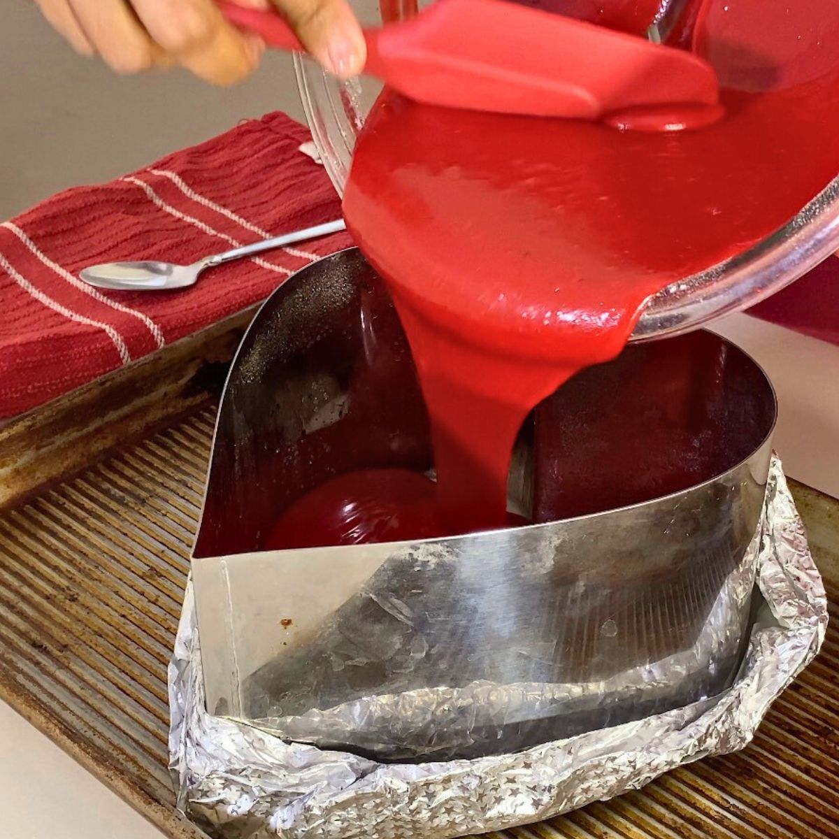 Progress pictures pouring red velvet cake batter into the heart pan.