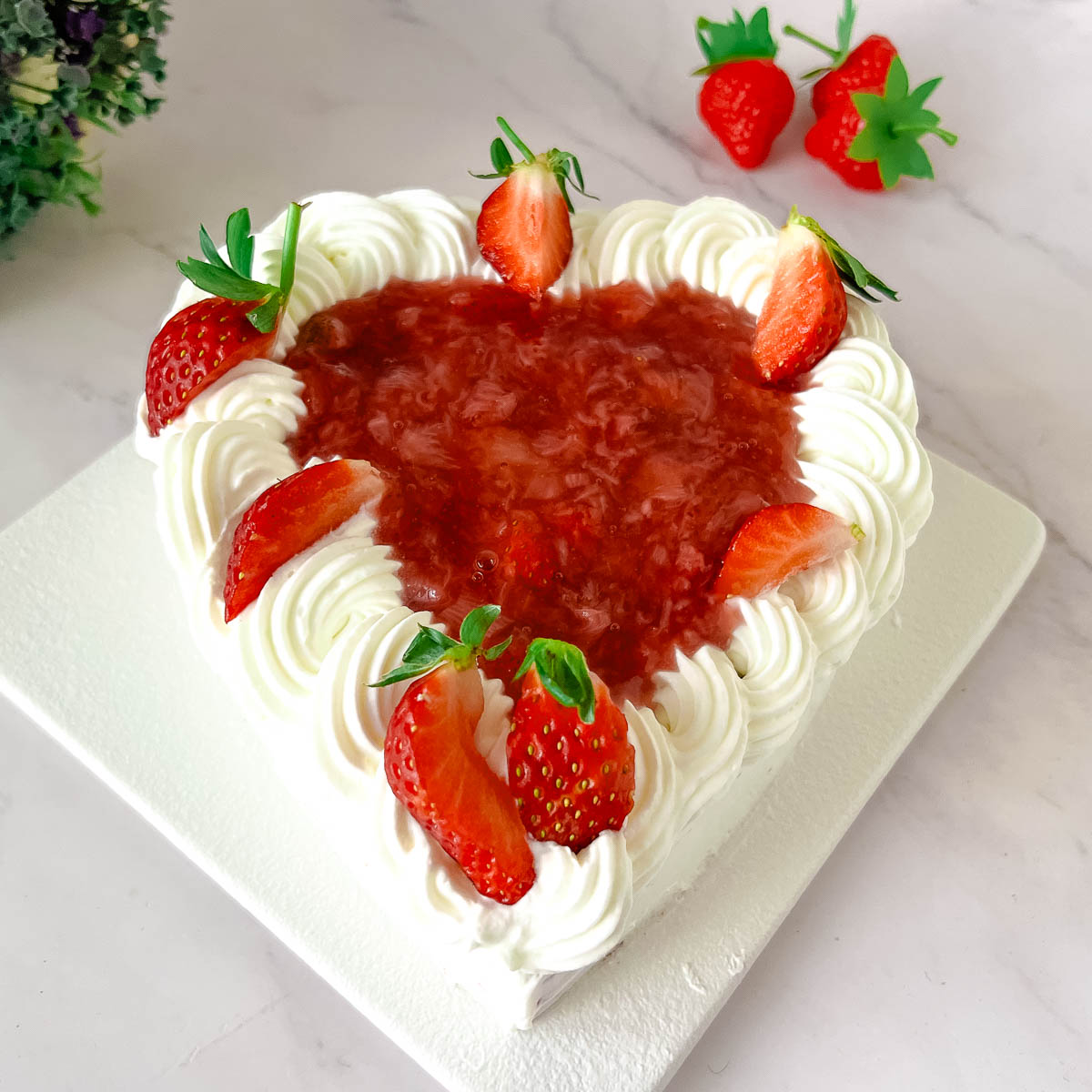 A frosted heart cake on the cake stand.
