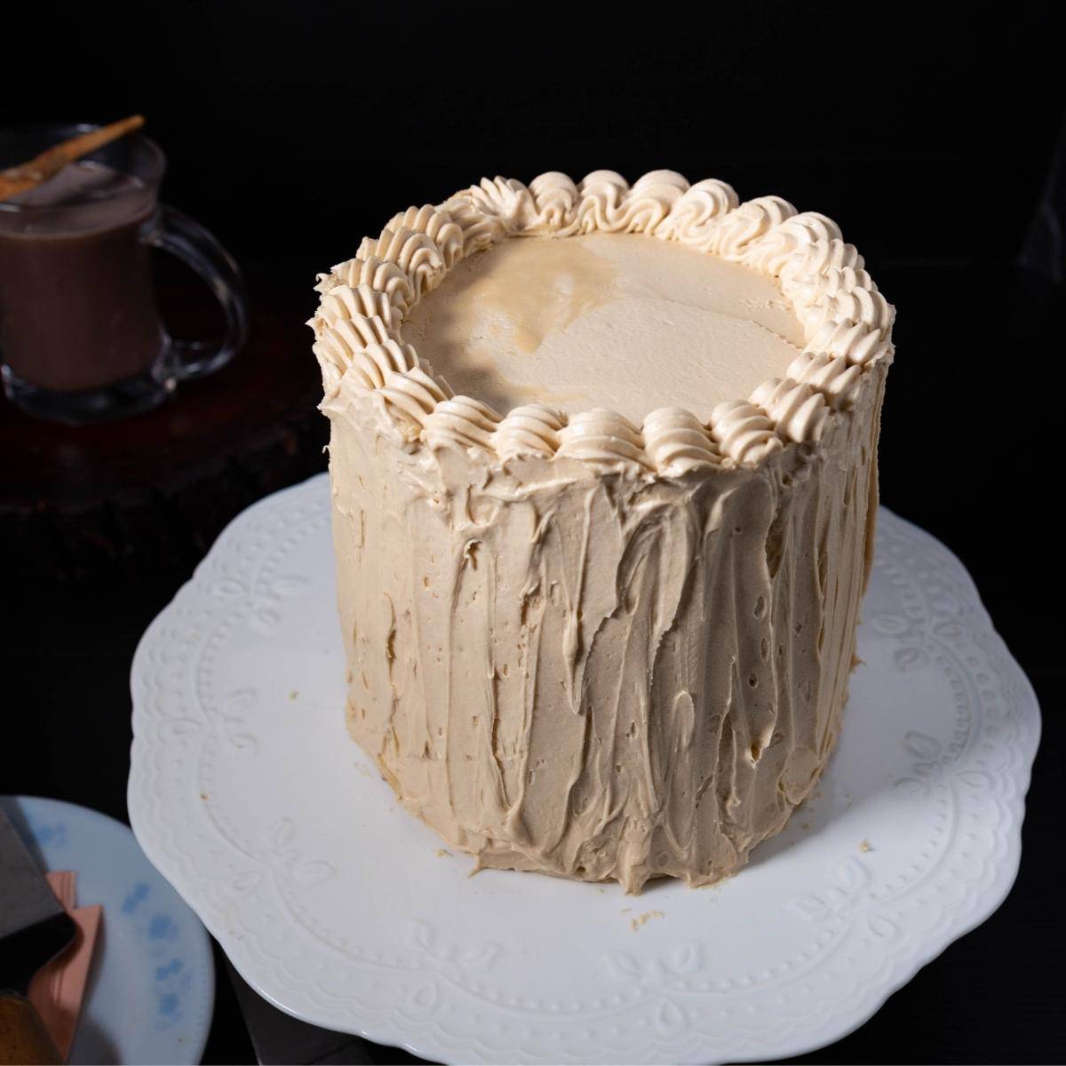 A cake with buttercream frosting on a stand.