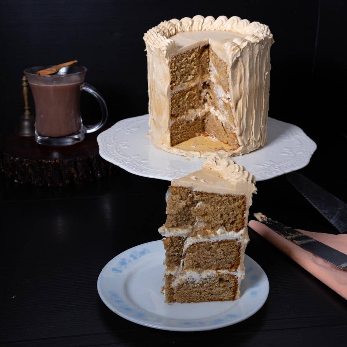 A slice of a layer cake with buttercream frosting on a plate.