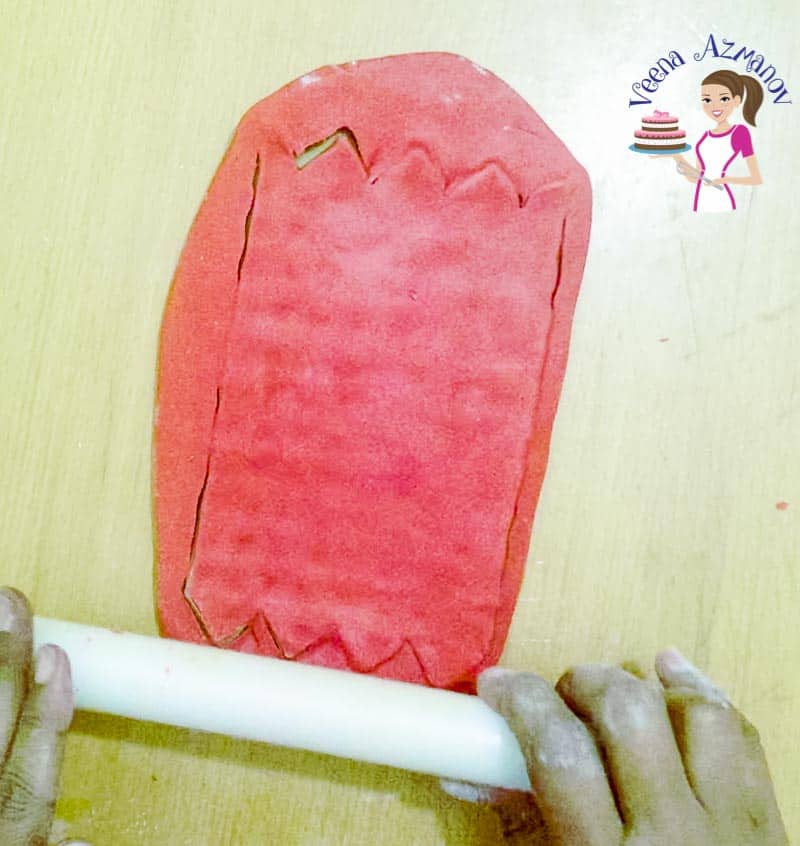 A person using a rolling pin to flatten fondant.