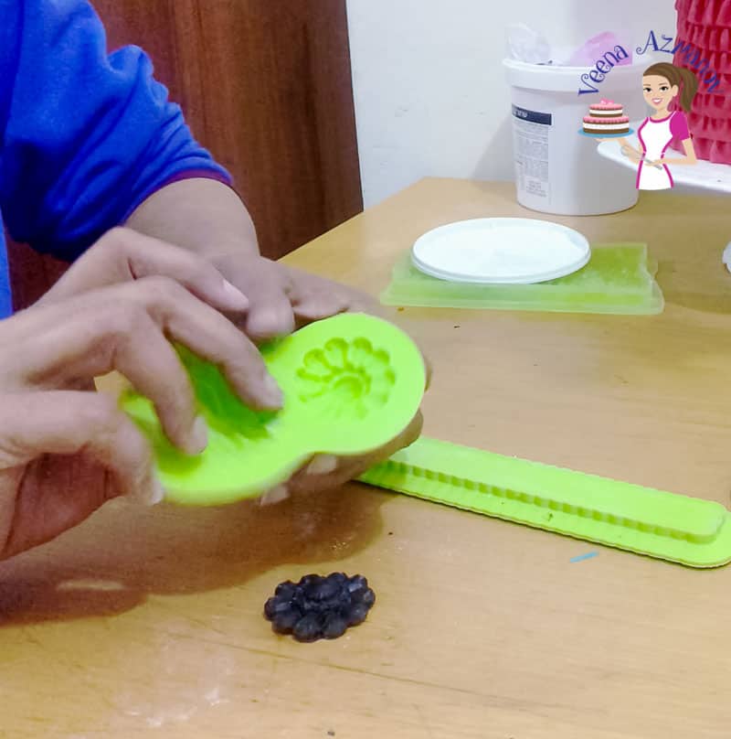 A person using silicon mold to create a fondant flower.