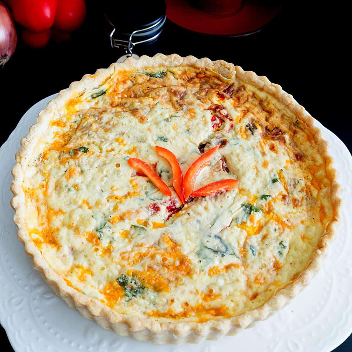 A baked quiche on a cake stand.