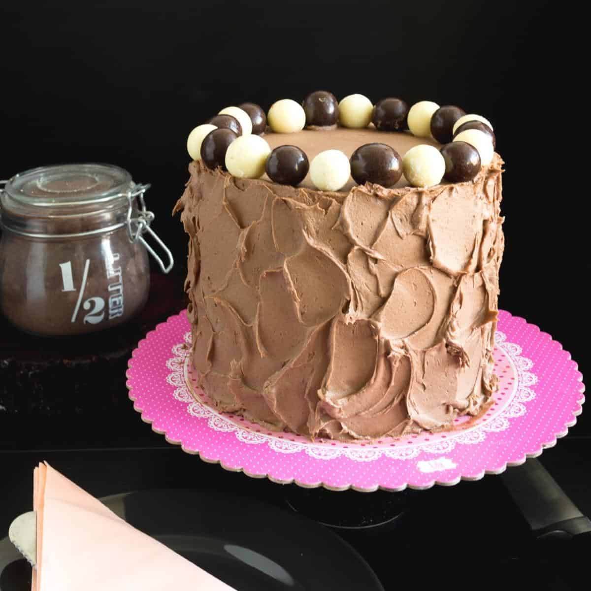 A frosted cake with chocolate balls.
