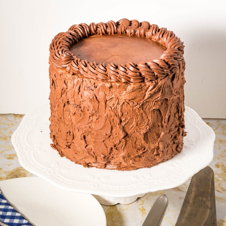 A frosted chocolate fudge cake on the table.