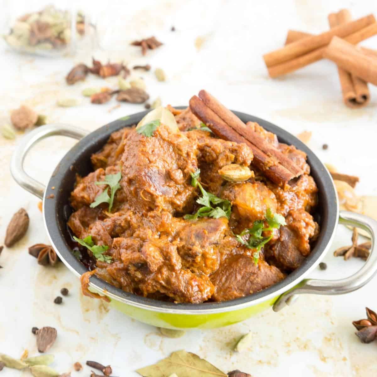 A serving kadai with cooked lamb.