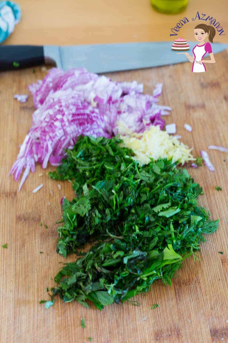 Chopped onions and herbs on a cutting board.