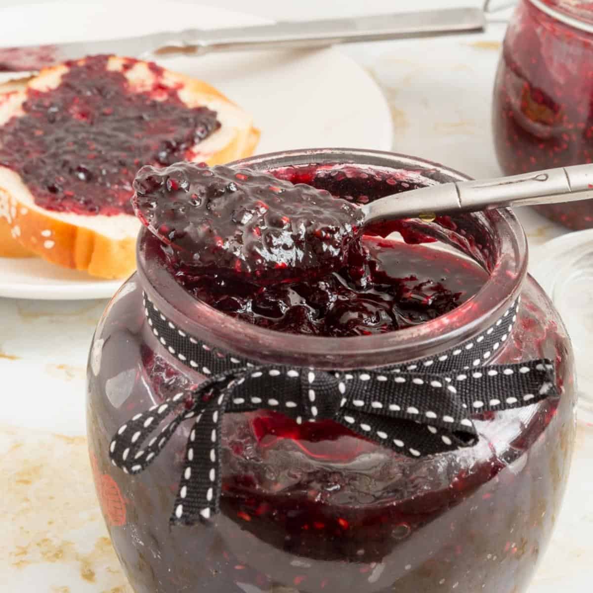 A jar and spoon with berry jam.
