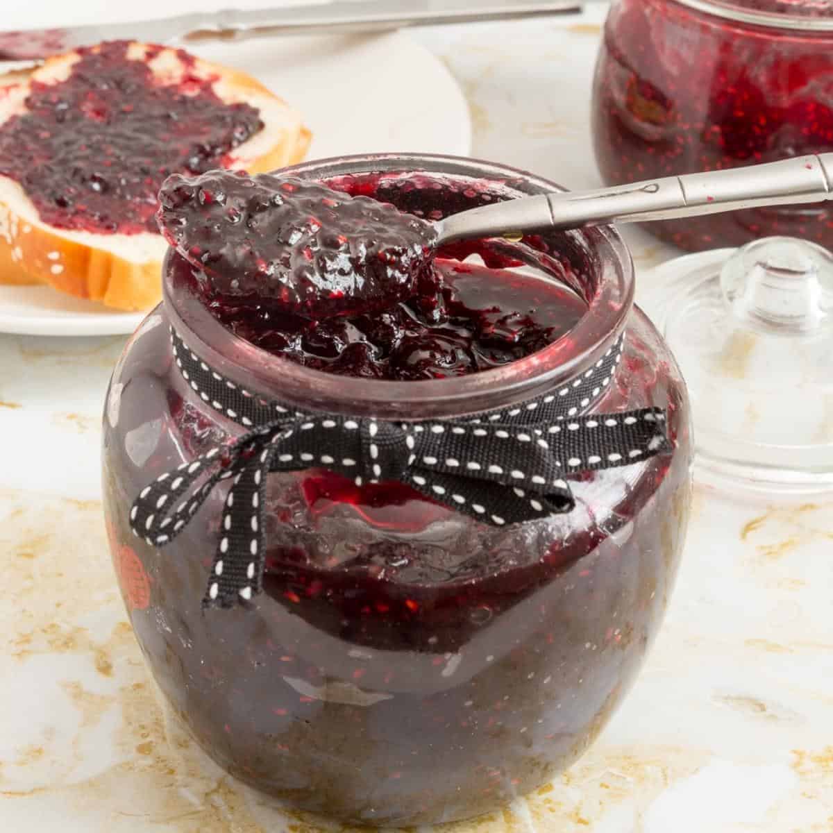 A jar and spoon with berry jam.
