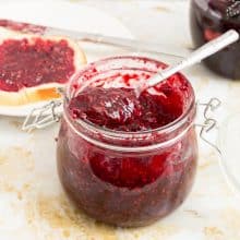 A mason jar with raspberries jam.