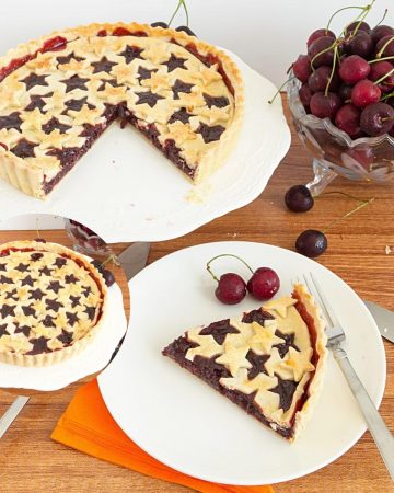 A pie with cherry filling on a cake stand.