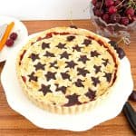 A pie with cherry filling on a cake stand.