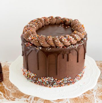 A decorated chocolate birthday cake on a white stand