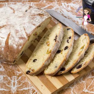 A sliced beer bread with olives on a cutting board.