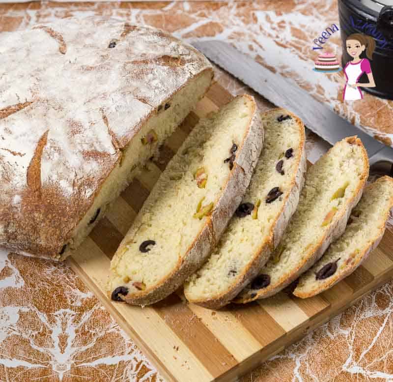 A sliced beer bread with olives on a cutting board.