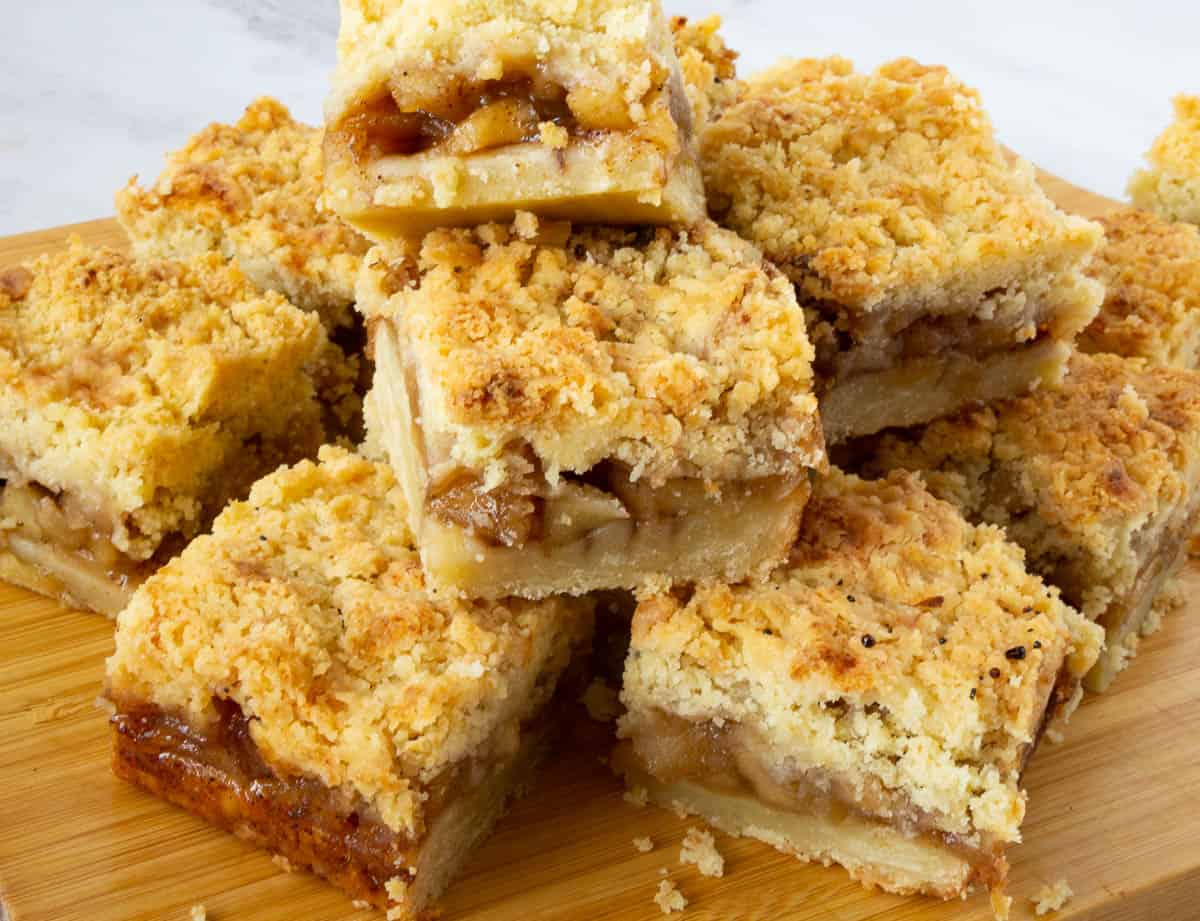 Apple pie bars stacked on a wooden board.