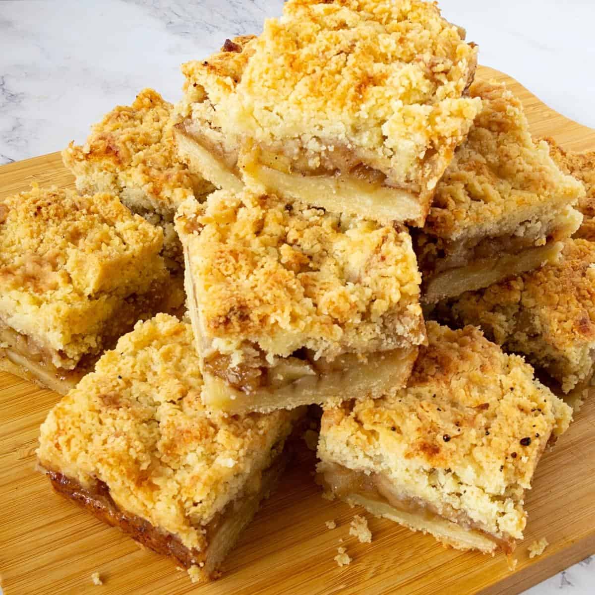 A stack of apple pie crumble bars on a wooden board.