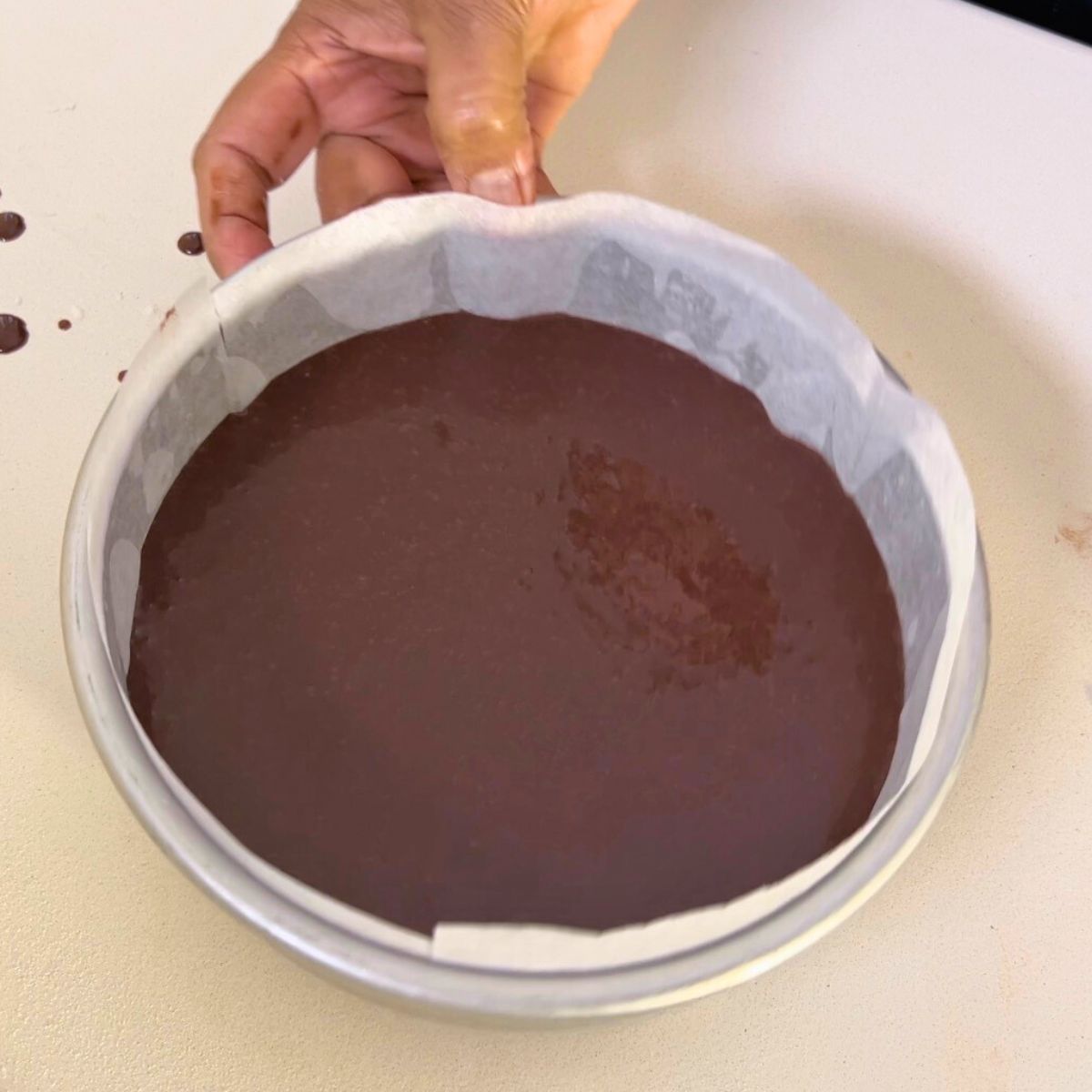 Chocolate cake batter in a cake pan for baking.