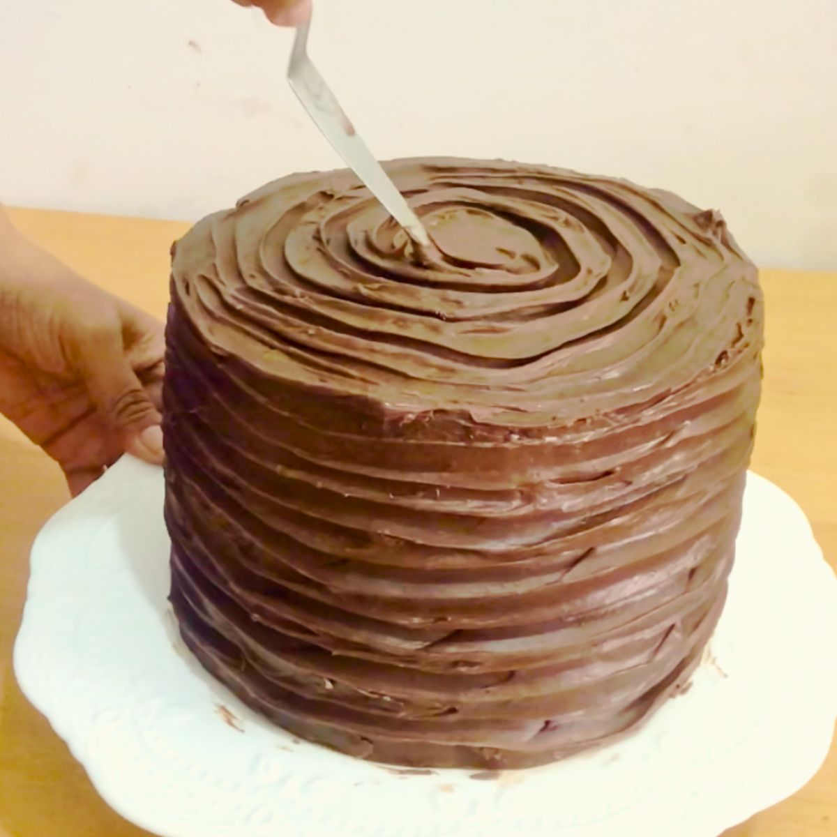 Frosting a chocolate cake with ganache.