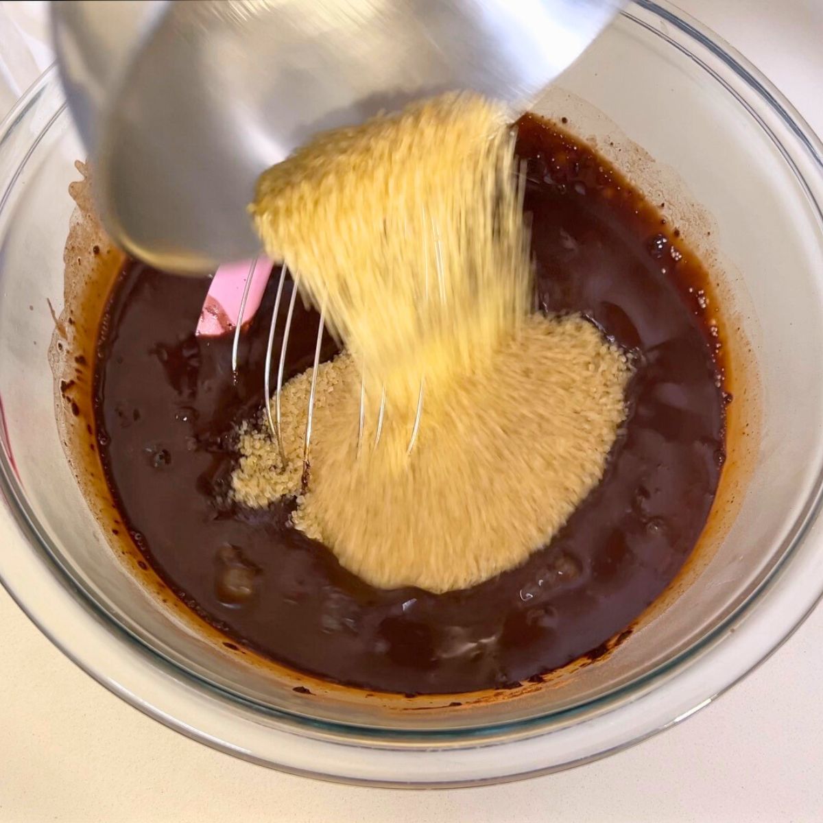 A glass bowl with sugar and cocoa powder and sugar.