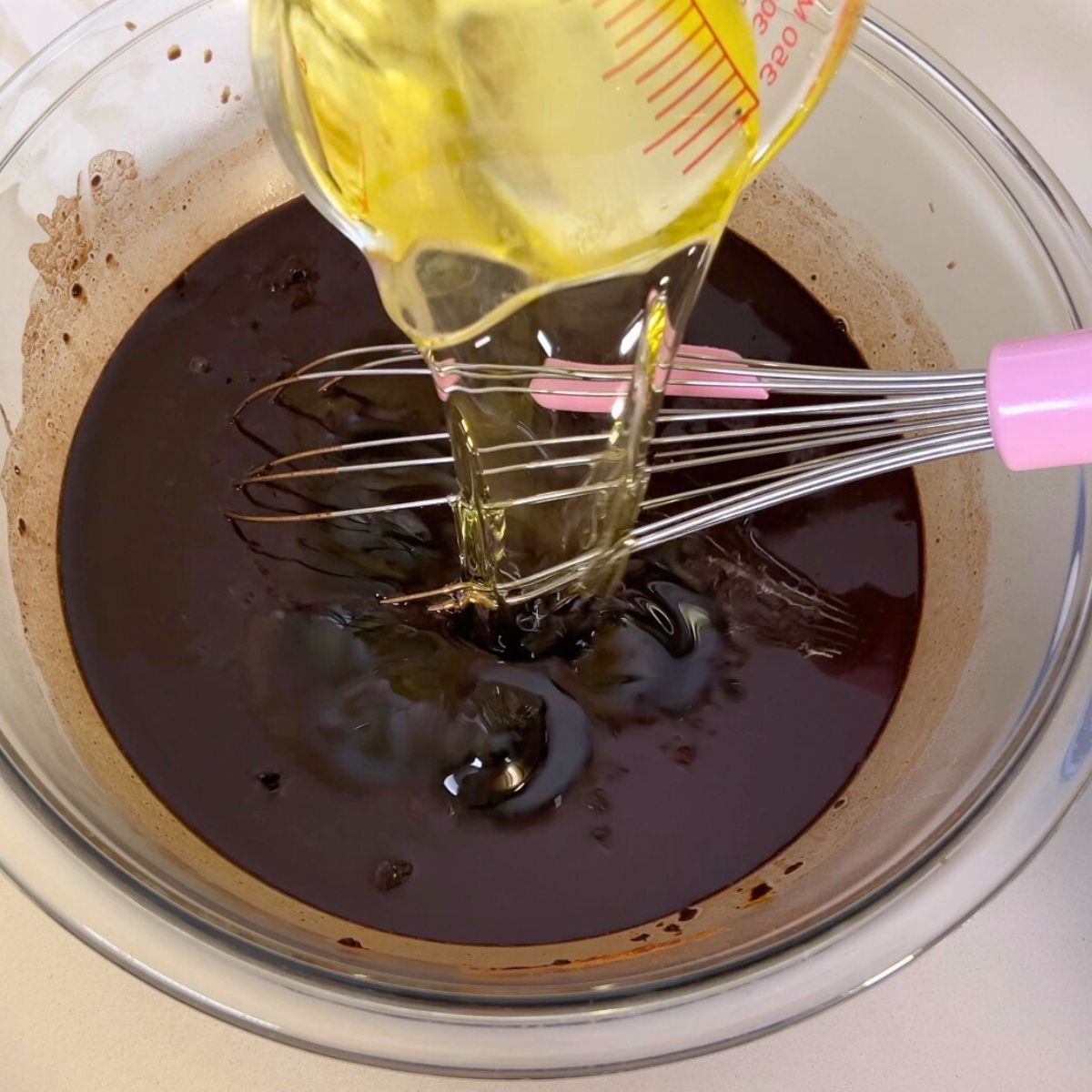 Adding oil to the glass bowl for cake batter.