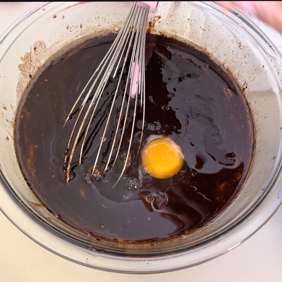A glass bowl with egg in cake batter.