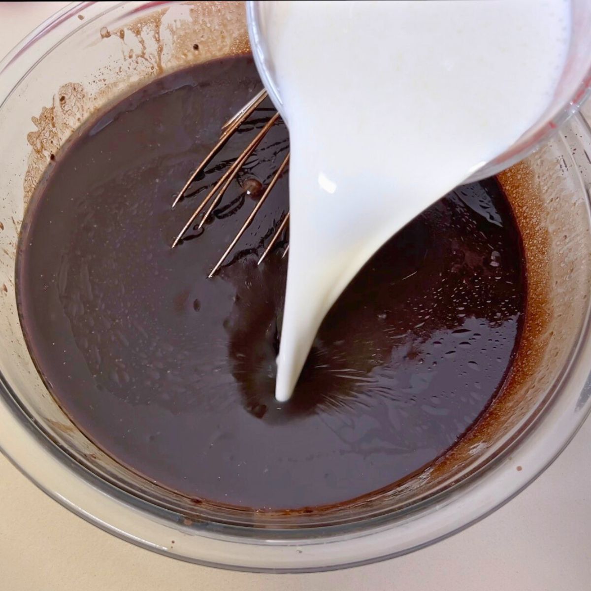 A glass bowl of buttermilk in the chocolate cake batter.