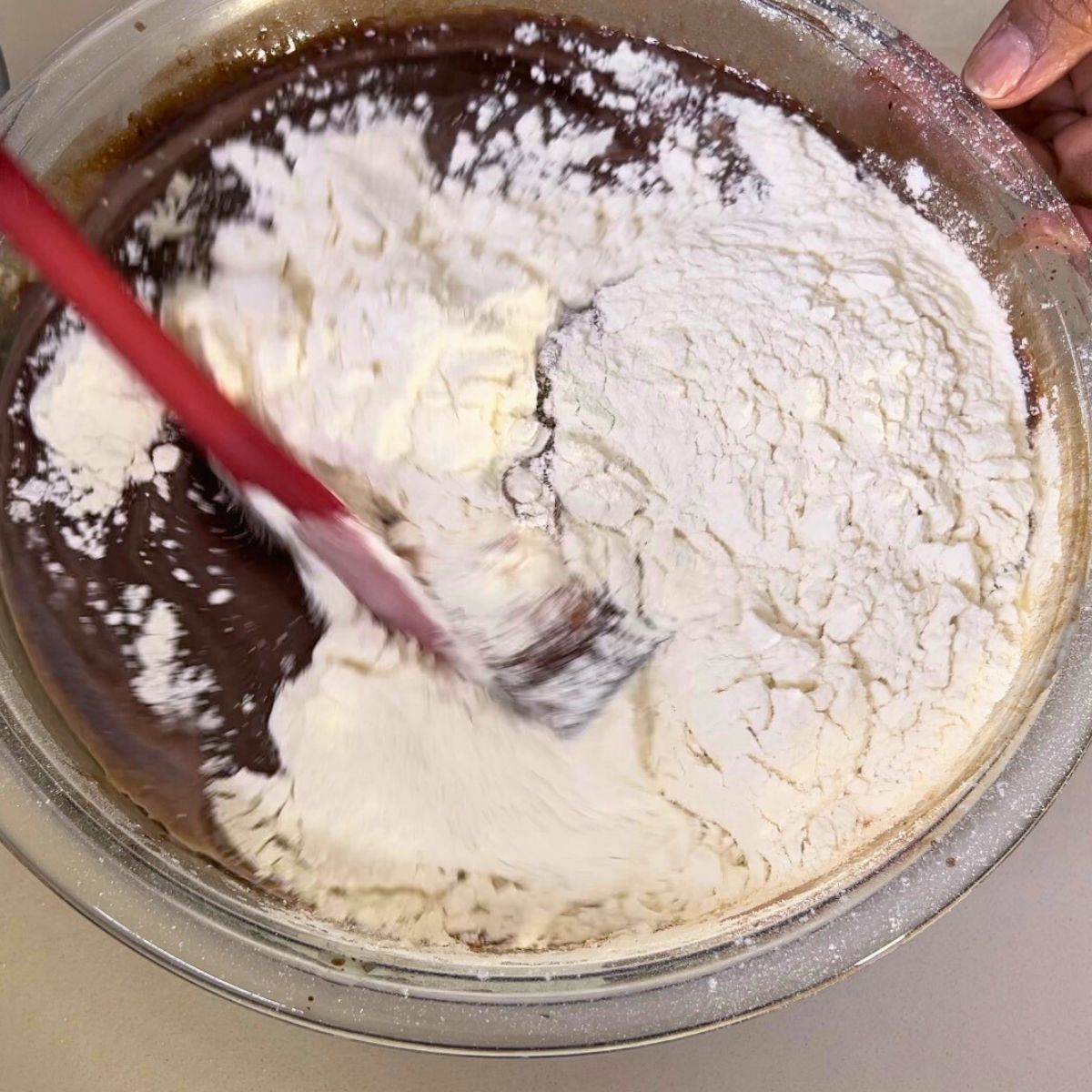 Adding flour to the chocolate cake batter.