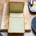A sliced loaf of sandwich bread on a wooden cutting board.