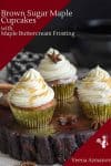 3 Cupcakes with maple buttercream frosting on a wooden stand.