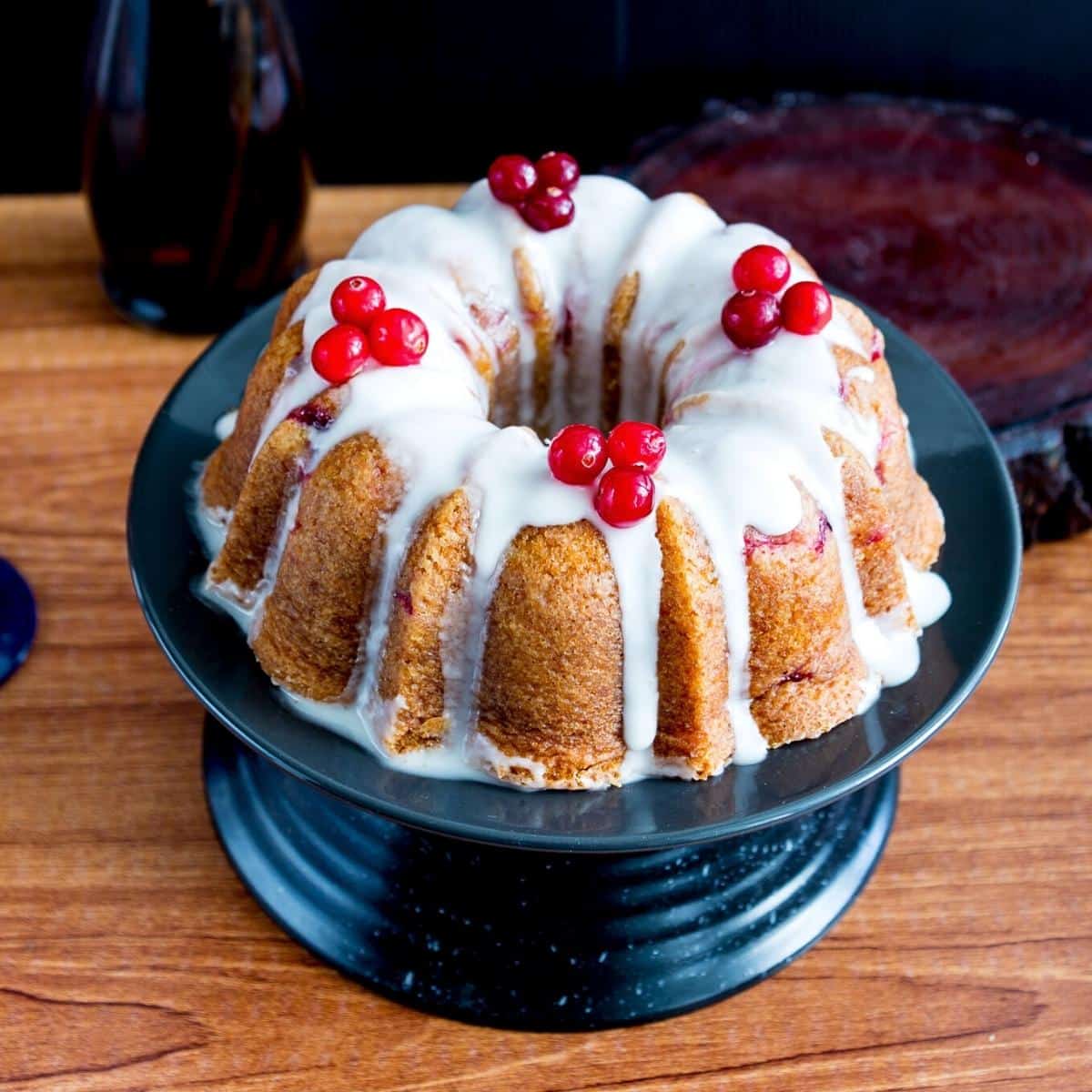 A bundt cake with fresh cranberries on cake stand.