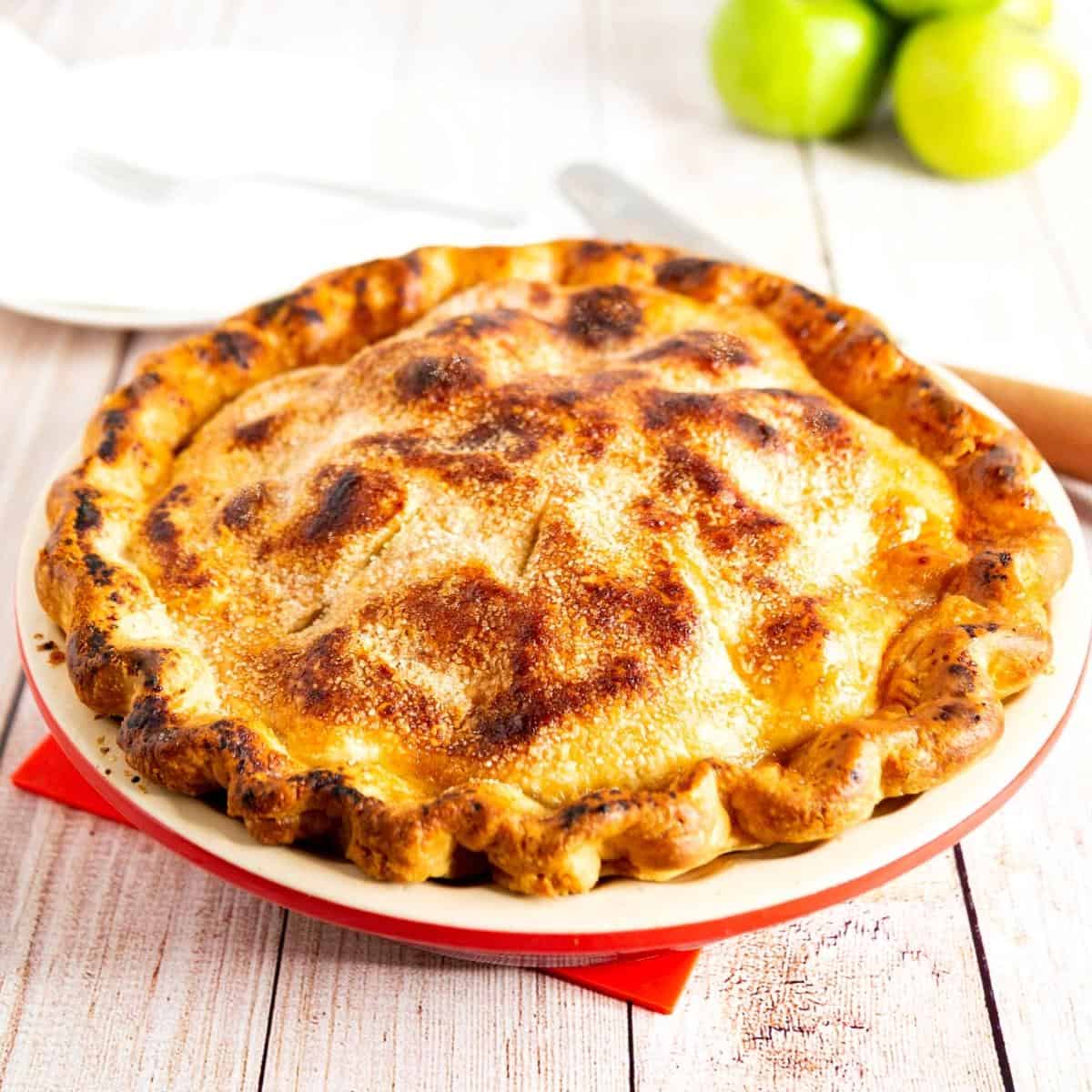 A pie in a pie pan with granny smith apples.
