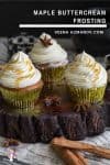 Three cupcakes with maple buttercream frosting on a wooden stand.