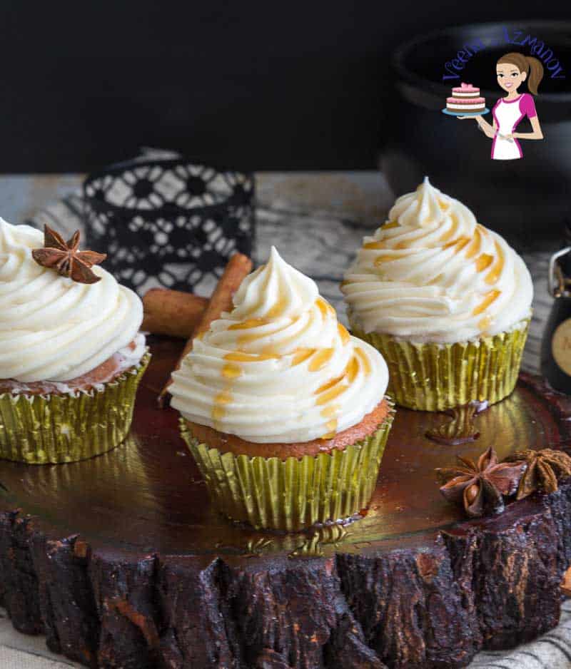 Three cupcakes with maple buttercream frosting on a table.