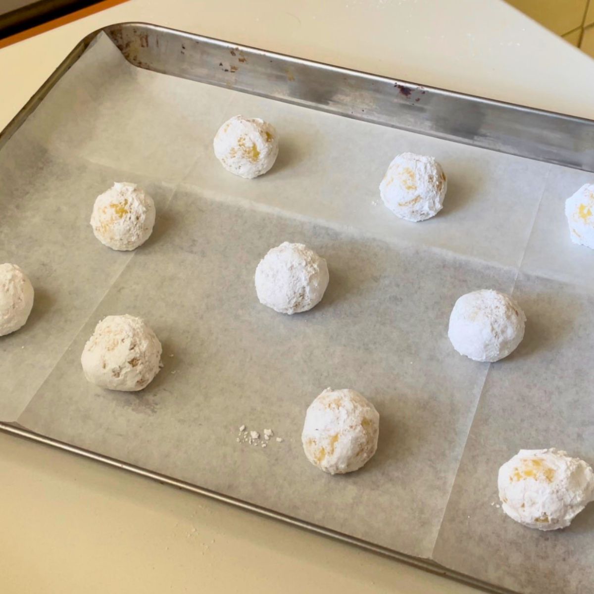 A baking tray with prebaked lemon crinkle cookies.
