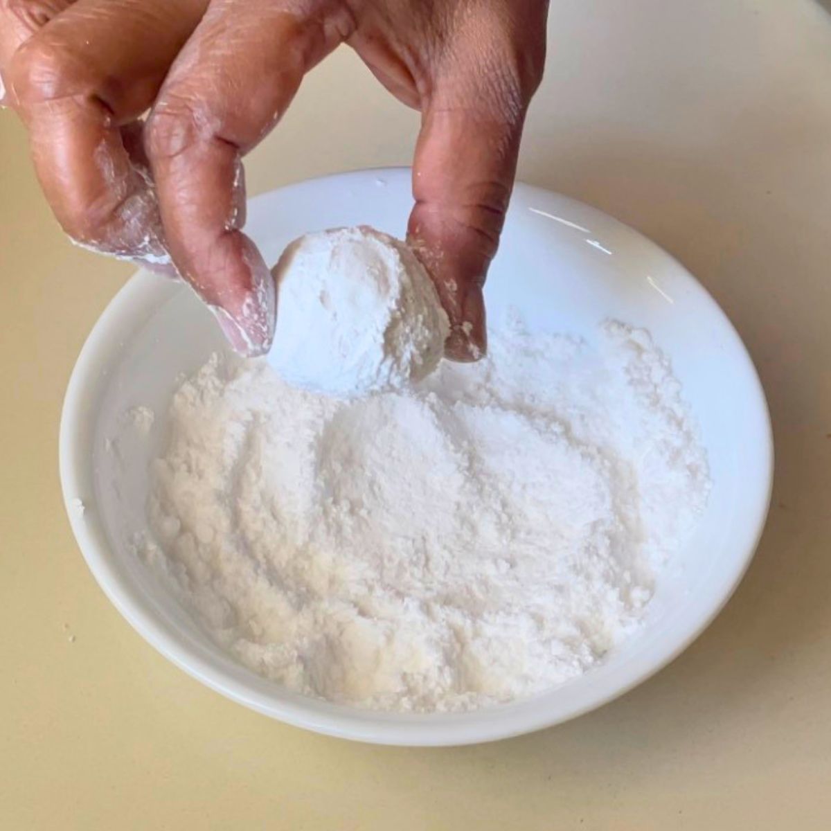 A white bowl with granulate sugar and powdered sugar.