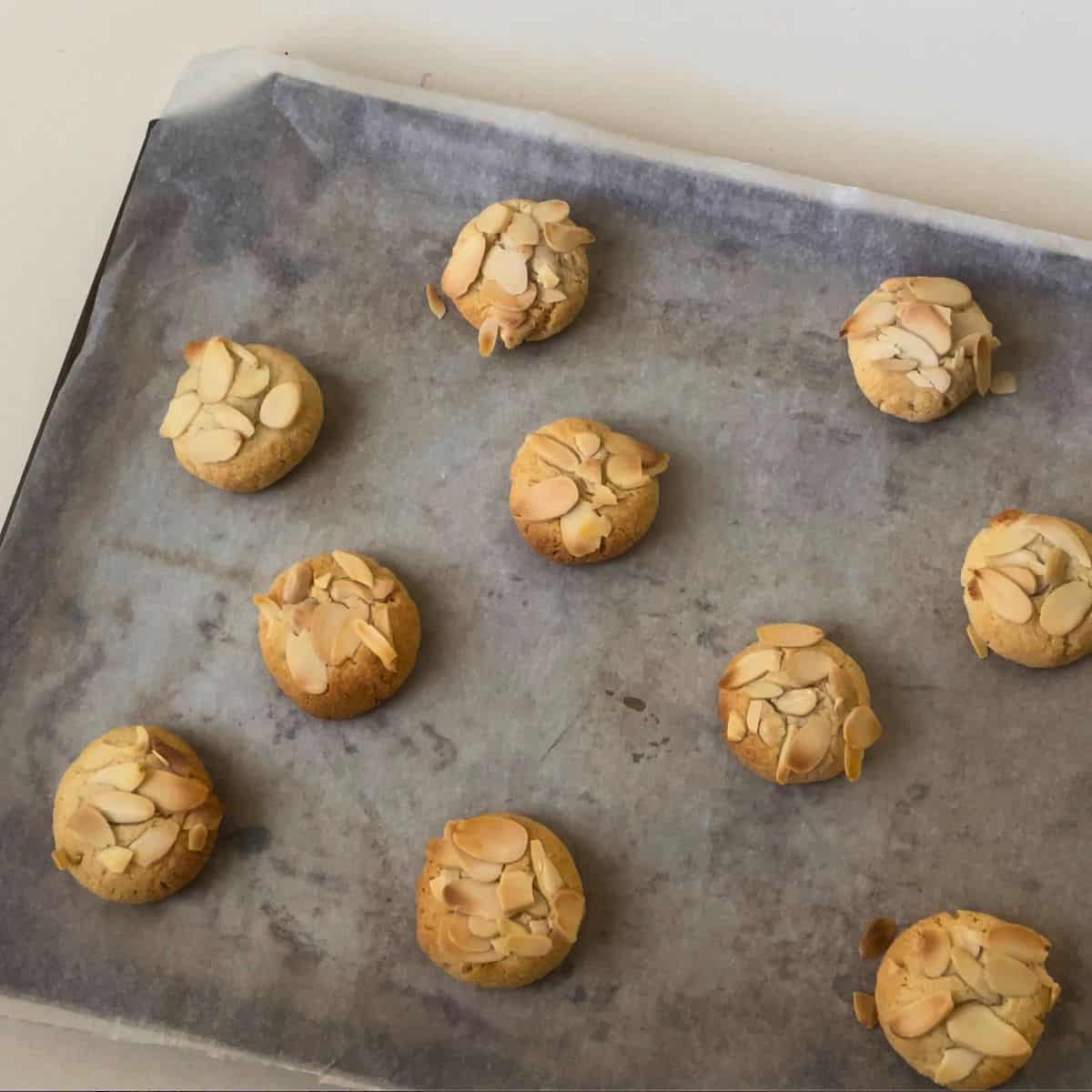Fresh baked almond cookies on a baking sheet.