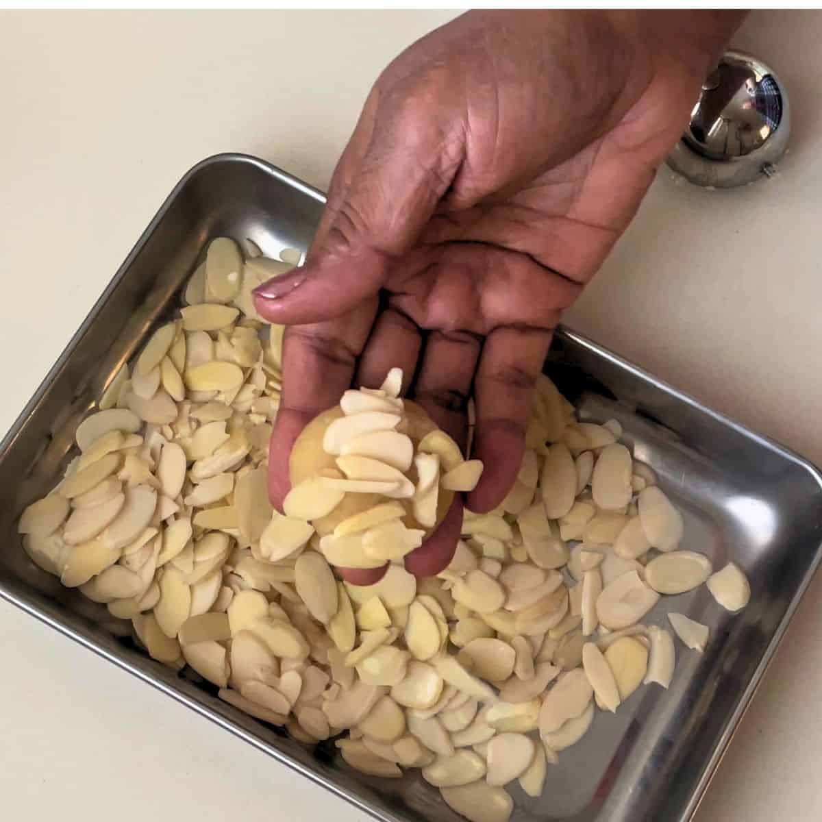 Pressing almond cookies with almond flakes before baking.