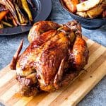 A roasted chicken on a wooden board.