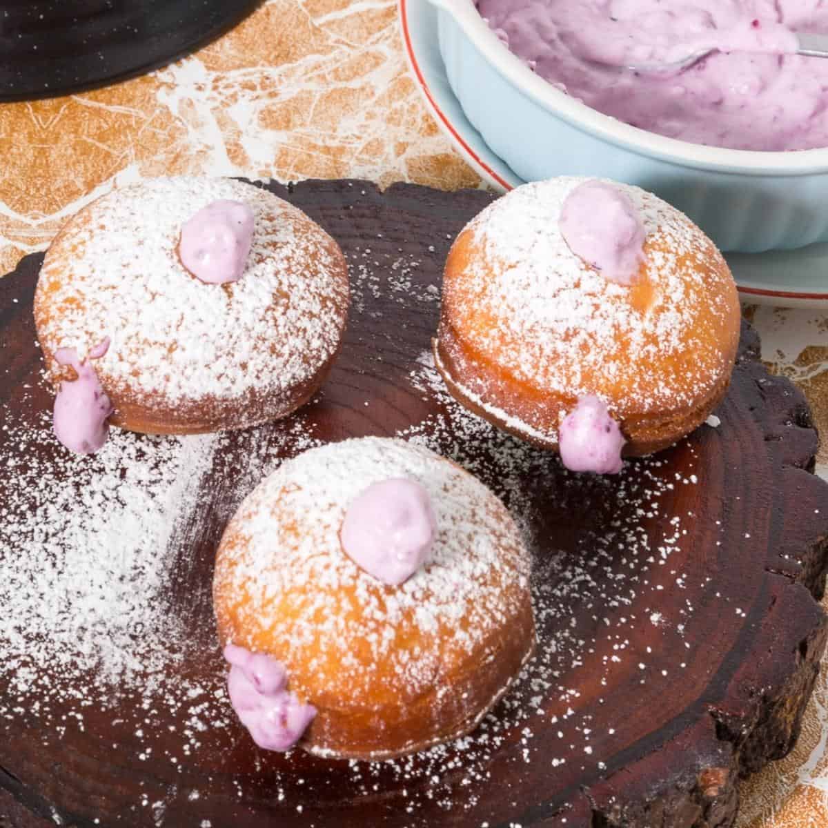 Donuts fill with blackberry cream on a wooden baord