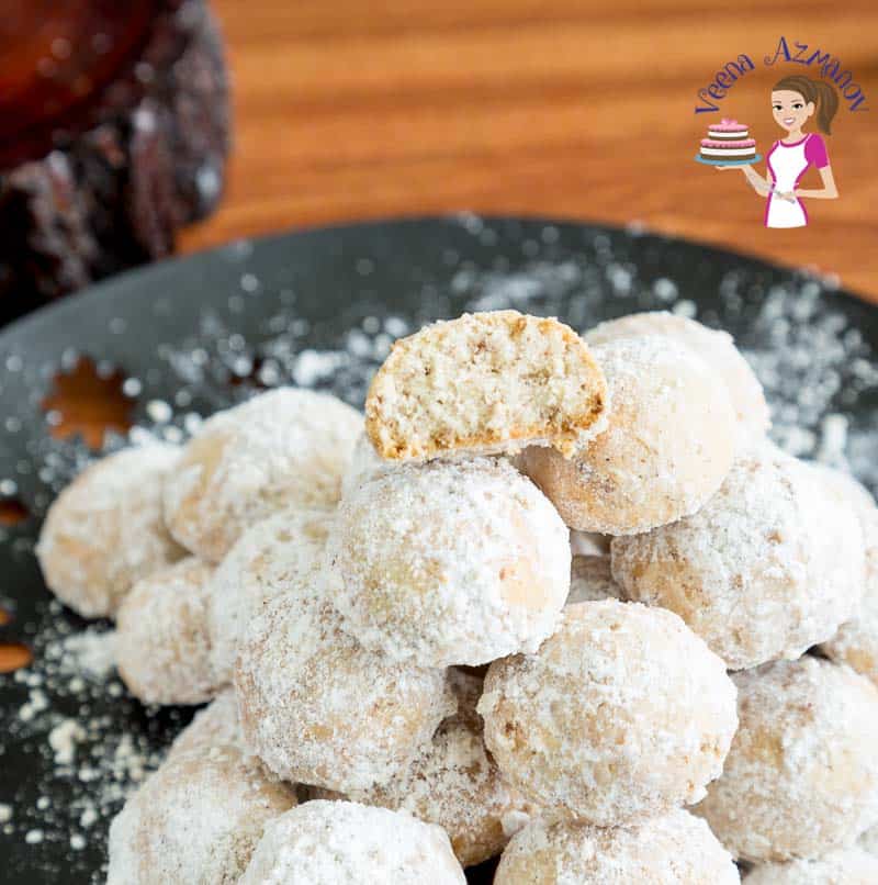 A stack of pecan snowball cookies on a plate.