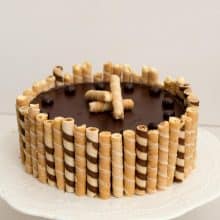 A flourless chocolate cake with wafers on a cake stand.