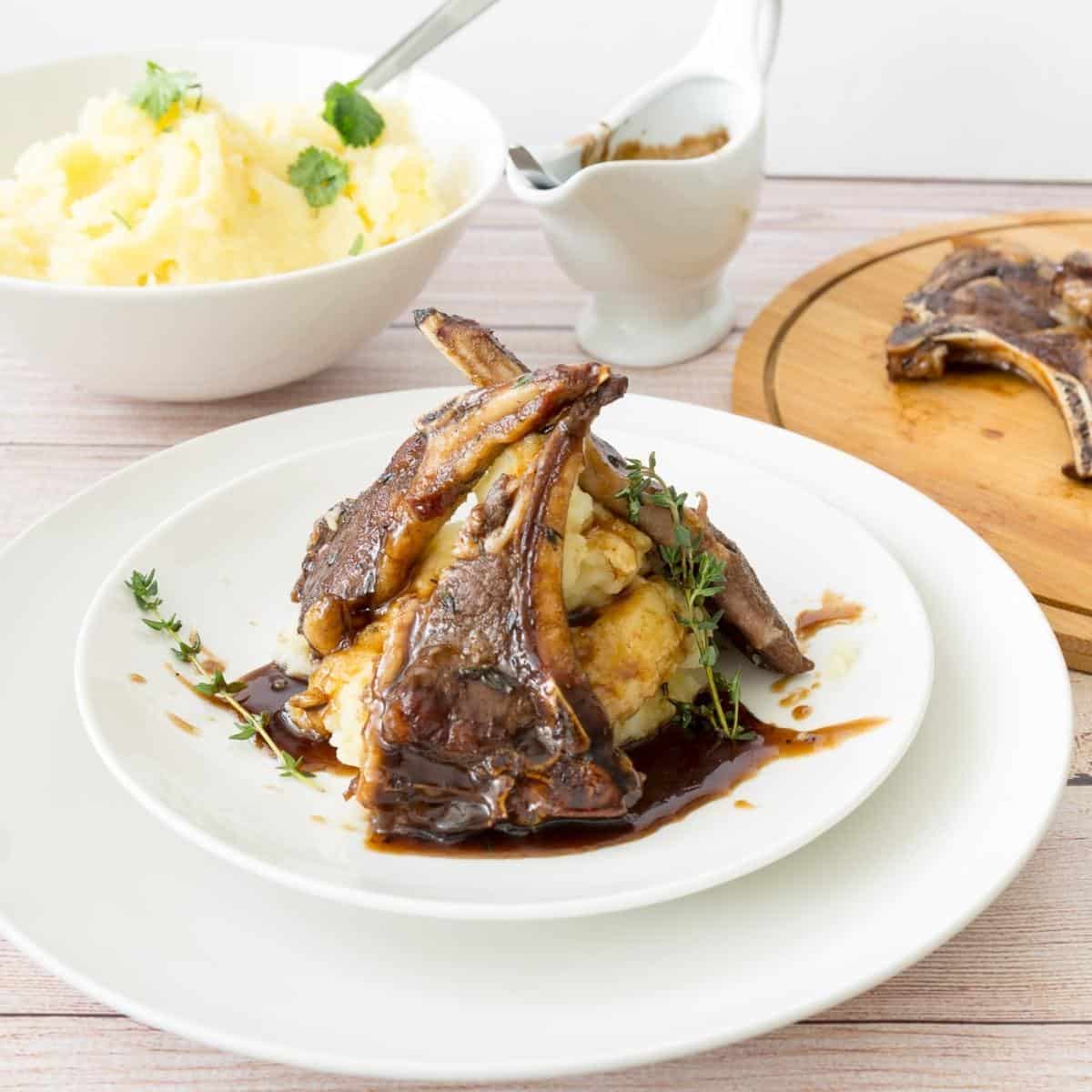 A plate of lamb chops with mashed potatoes.